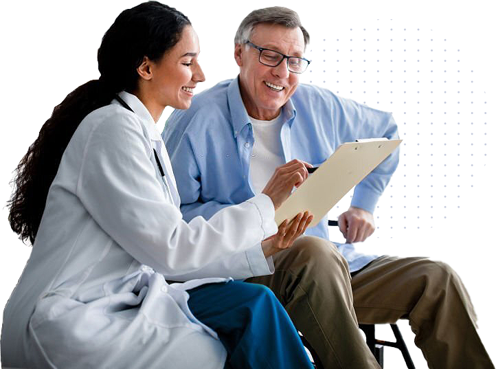 A smiling female doctor sits with an older male patient, reviewing information together on a clipboard